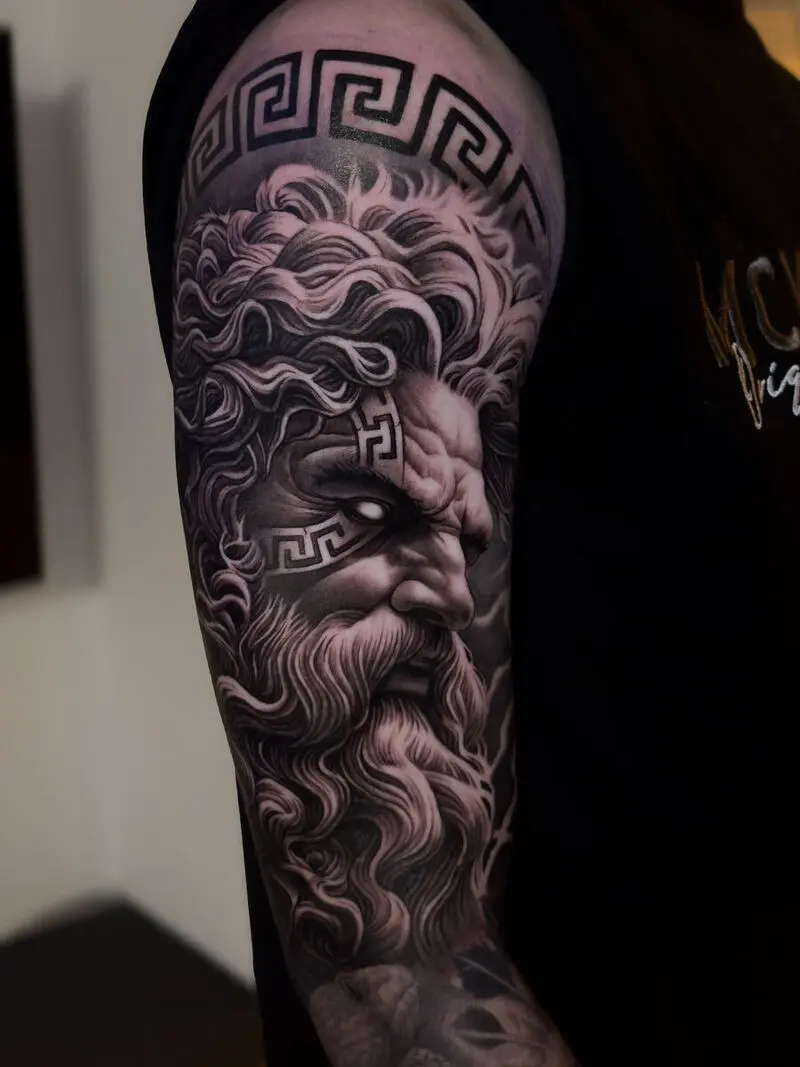 Tatuagem realista de rosto de Zeus com padrão grego meandro, preto e cinza