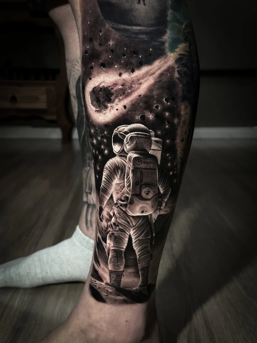 Tatuagem realista de astronauta no espaço em perna, preto e cinza